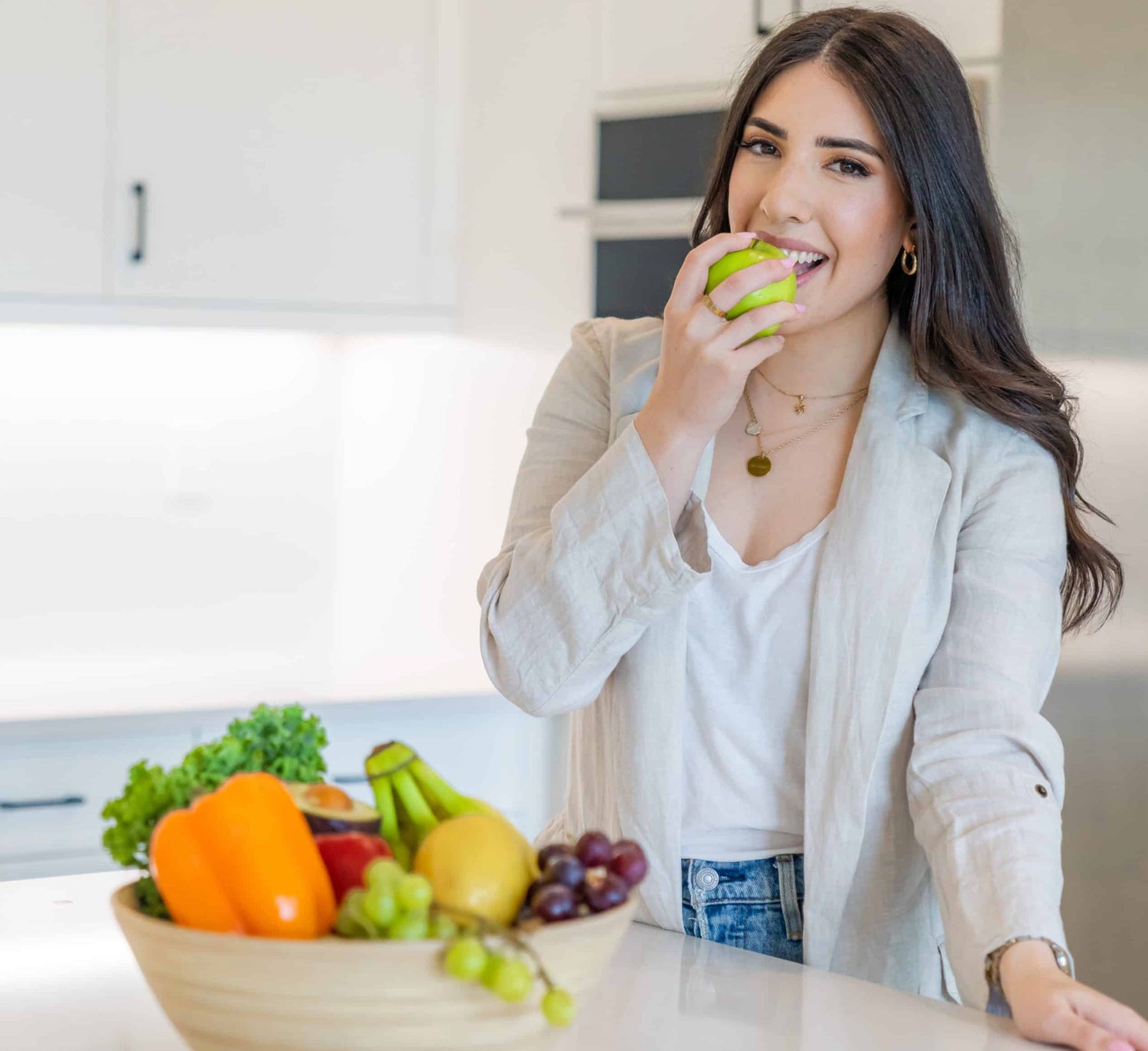 Danielle Brown biting apple with fresh fruits