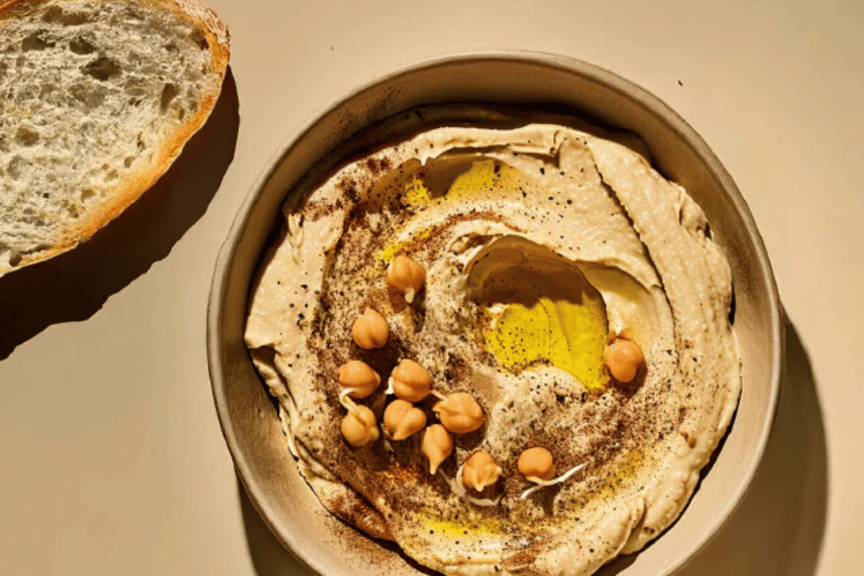 A bowl of creamy hummus topped with whole chickpeas, a drizzle of olive oil, and spices