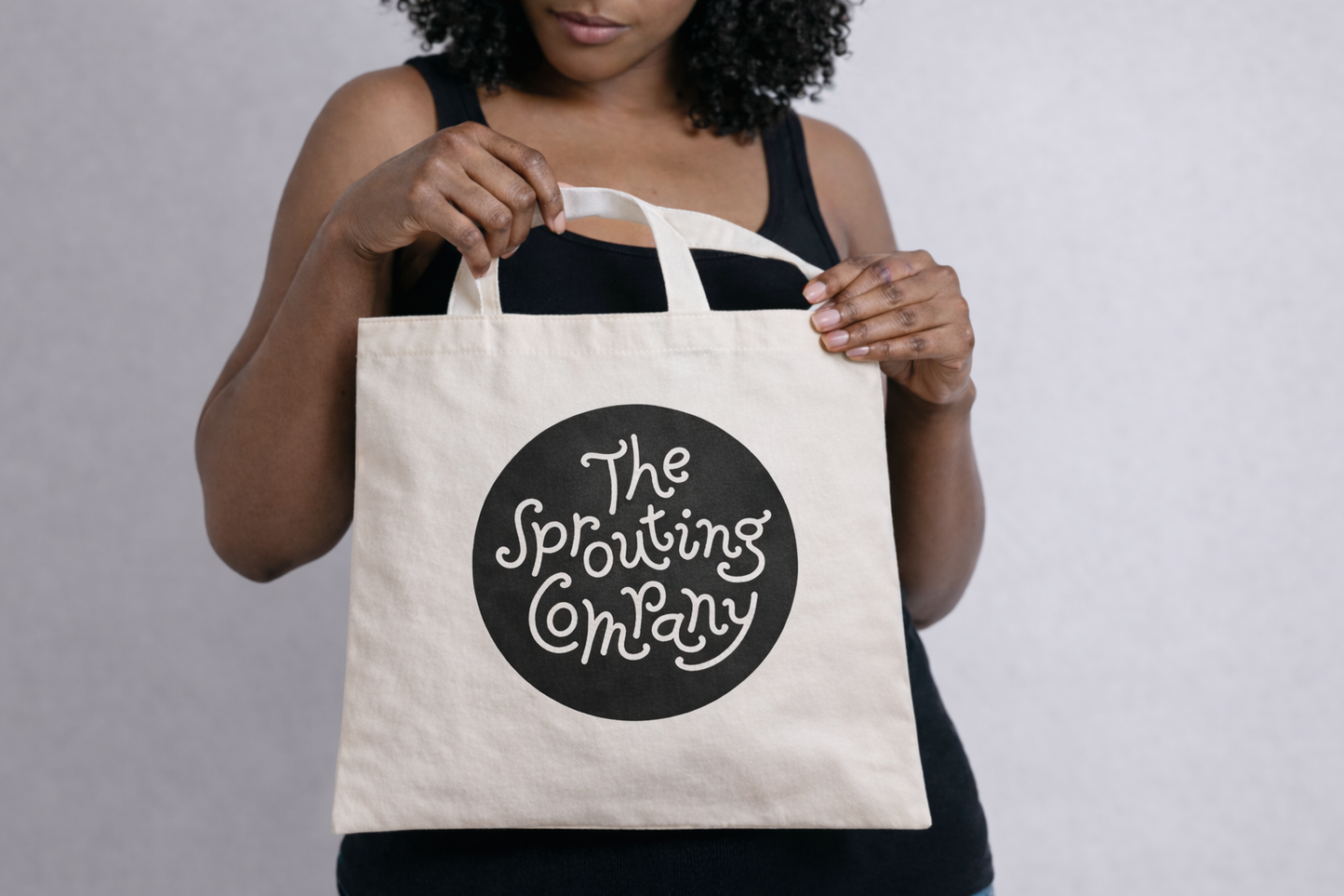 Person holding Sprouting Company logo tote